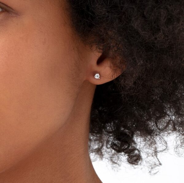 A woman with afro hair wearing diamond stud earrings.
