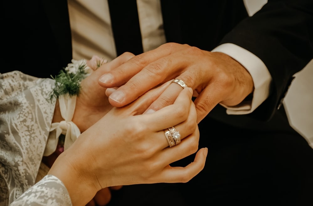 Woman putting wedding band on man's hand