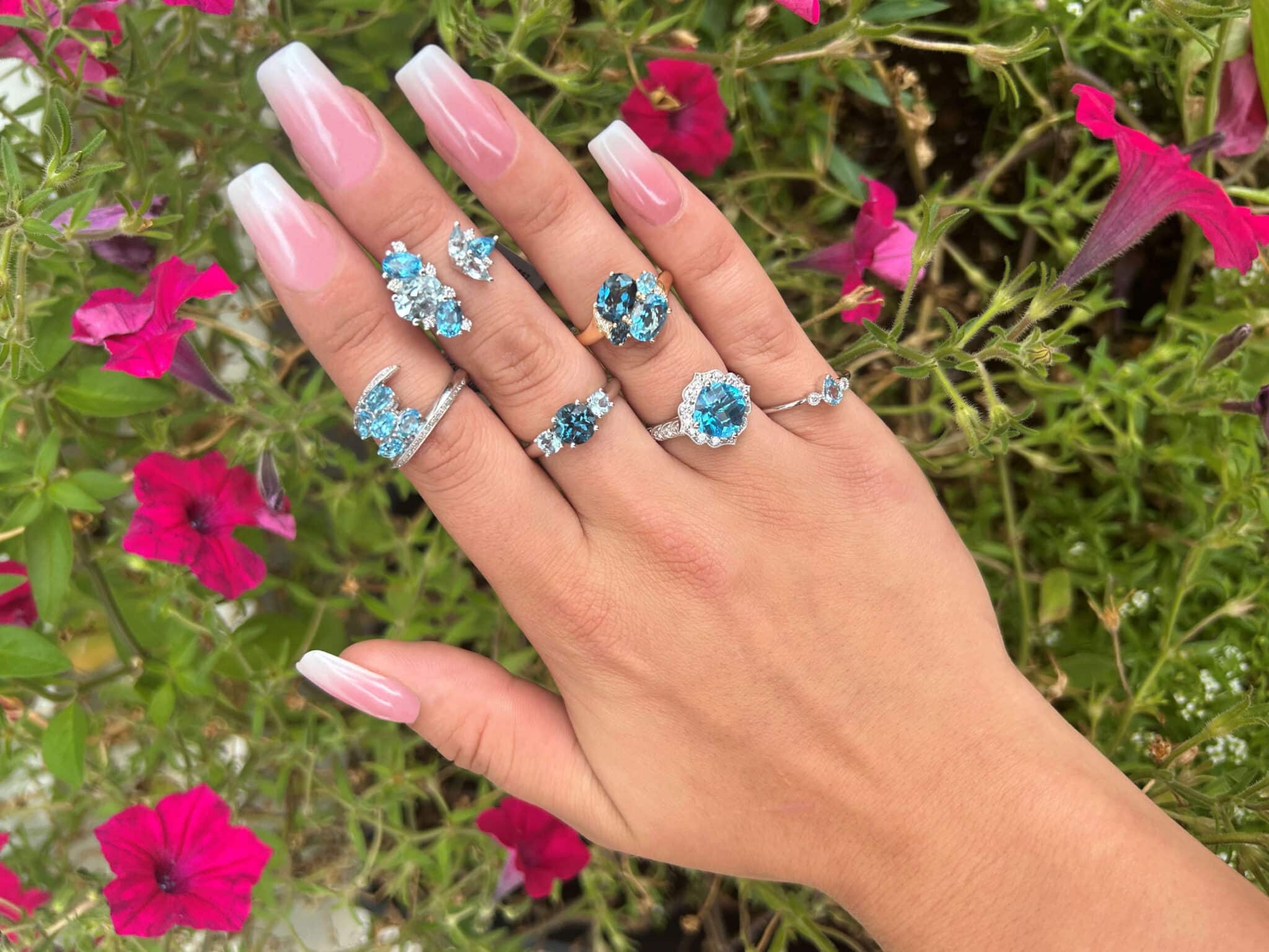 Woman's hand wearing 6 blue topaz rings