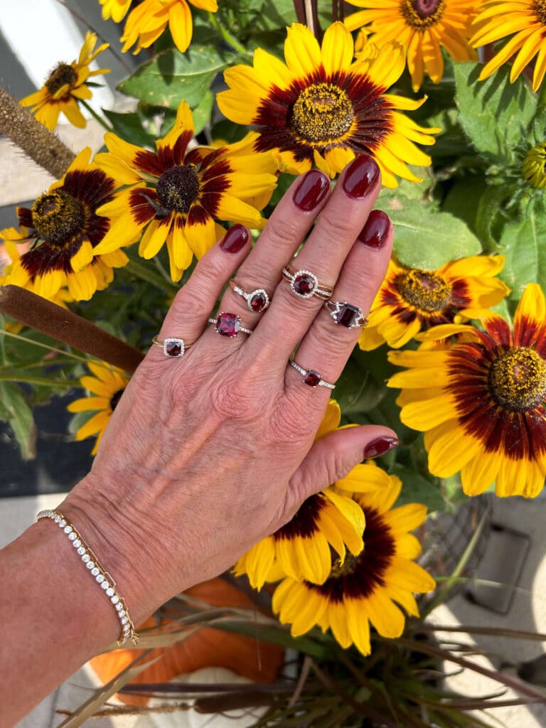 Woman's hand wearing 6 garnet rings